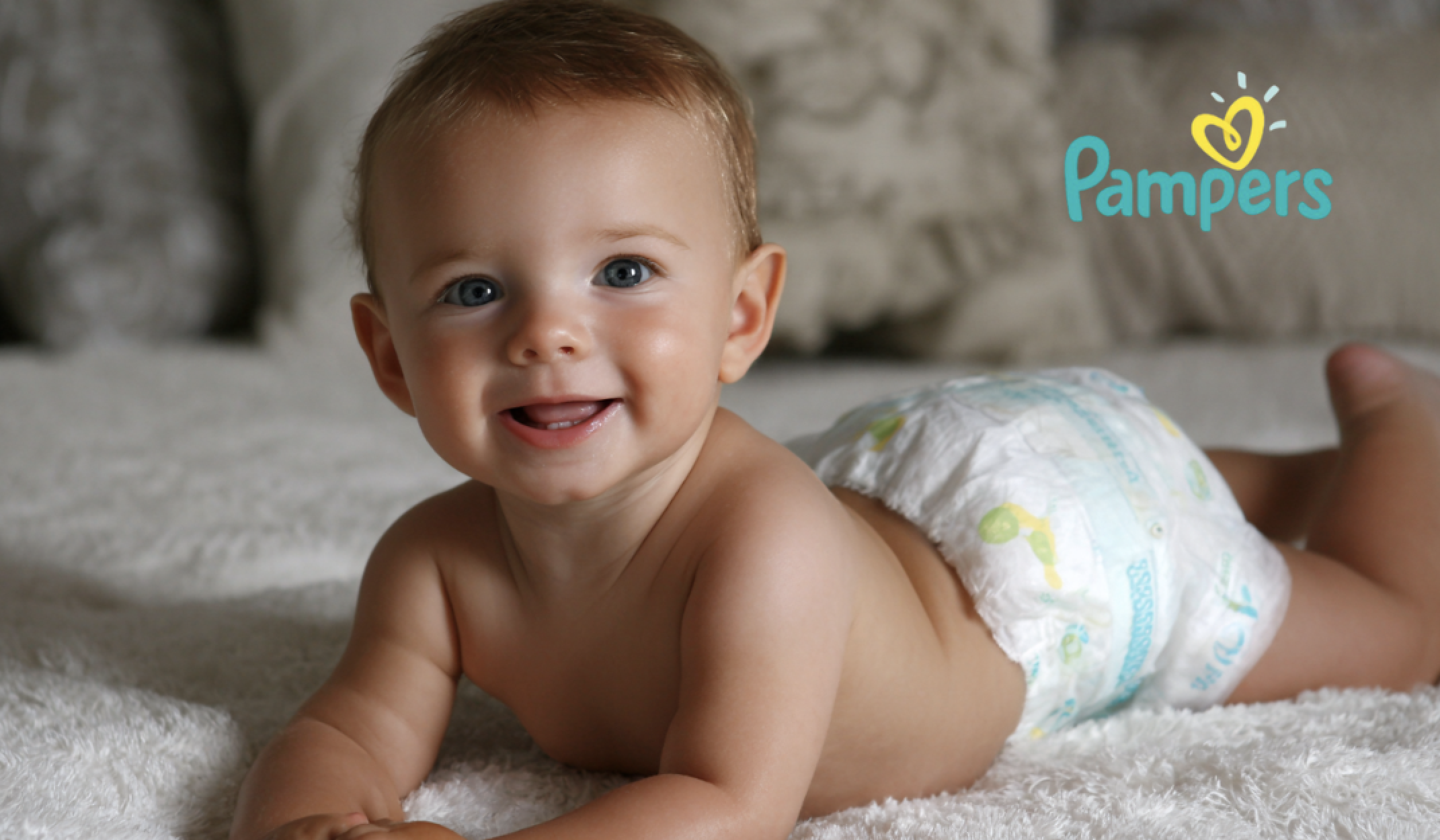 Baby in diaper smiling on soft bed