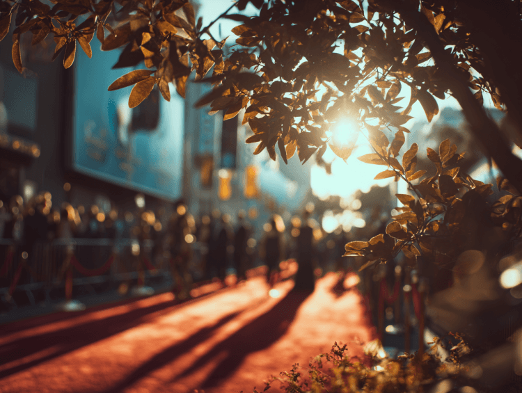 Sunlit red carpet event with leafy foreground.