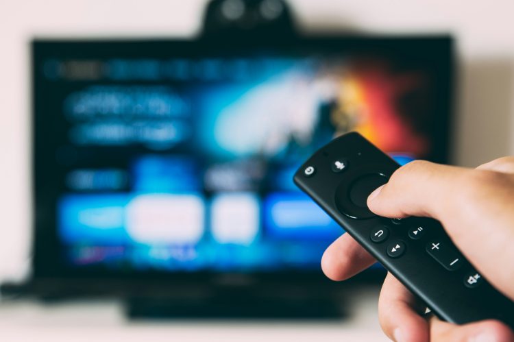Person using remote control with smart TV screen