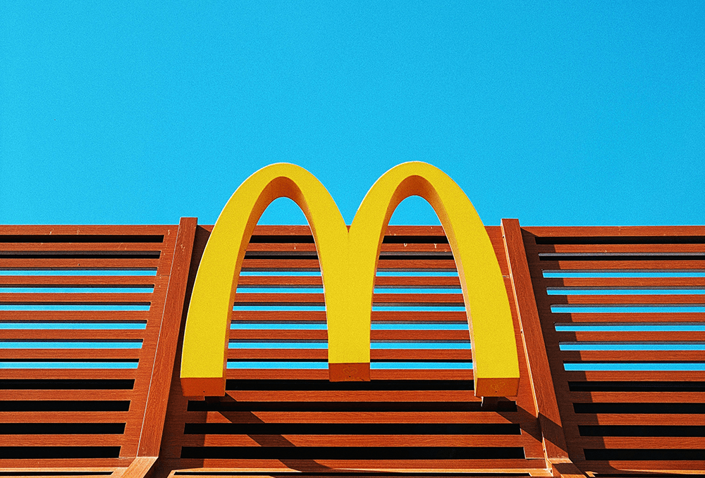 Golden arches on wooden structure, clear blue sky.