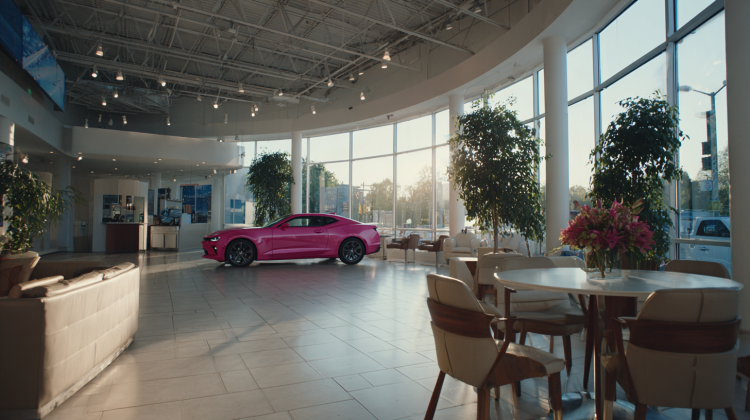 Bright pink car in modern showroom interior.