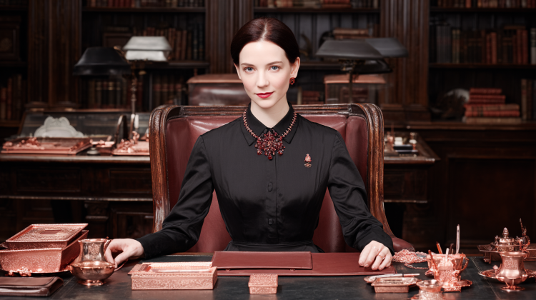 Woman in ornate office with copper decor.