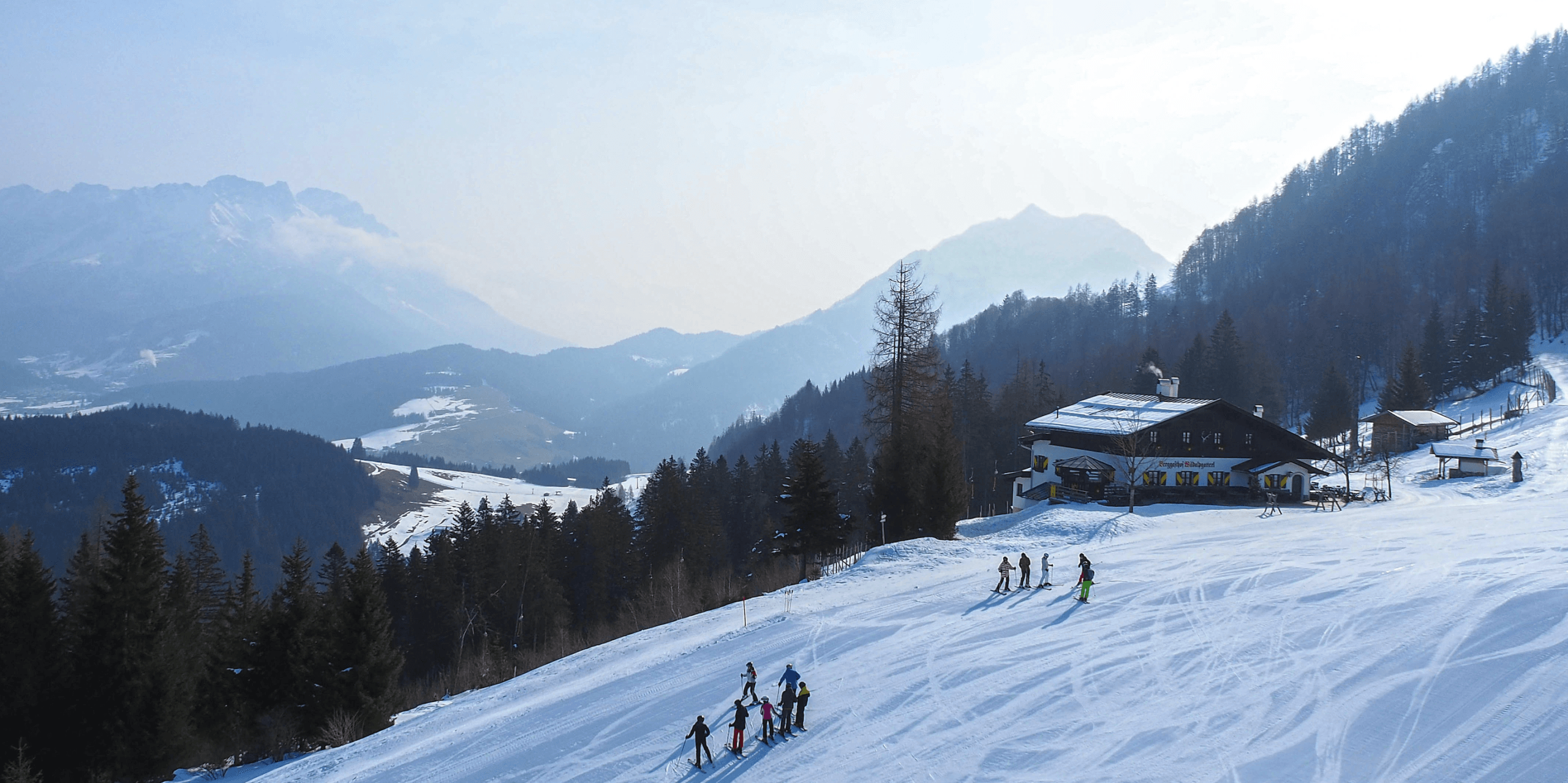 Skiers on snowy mountain slope near chalet