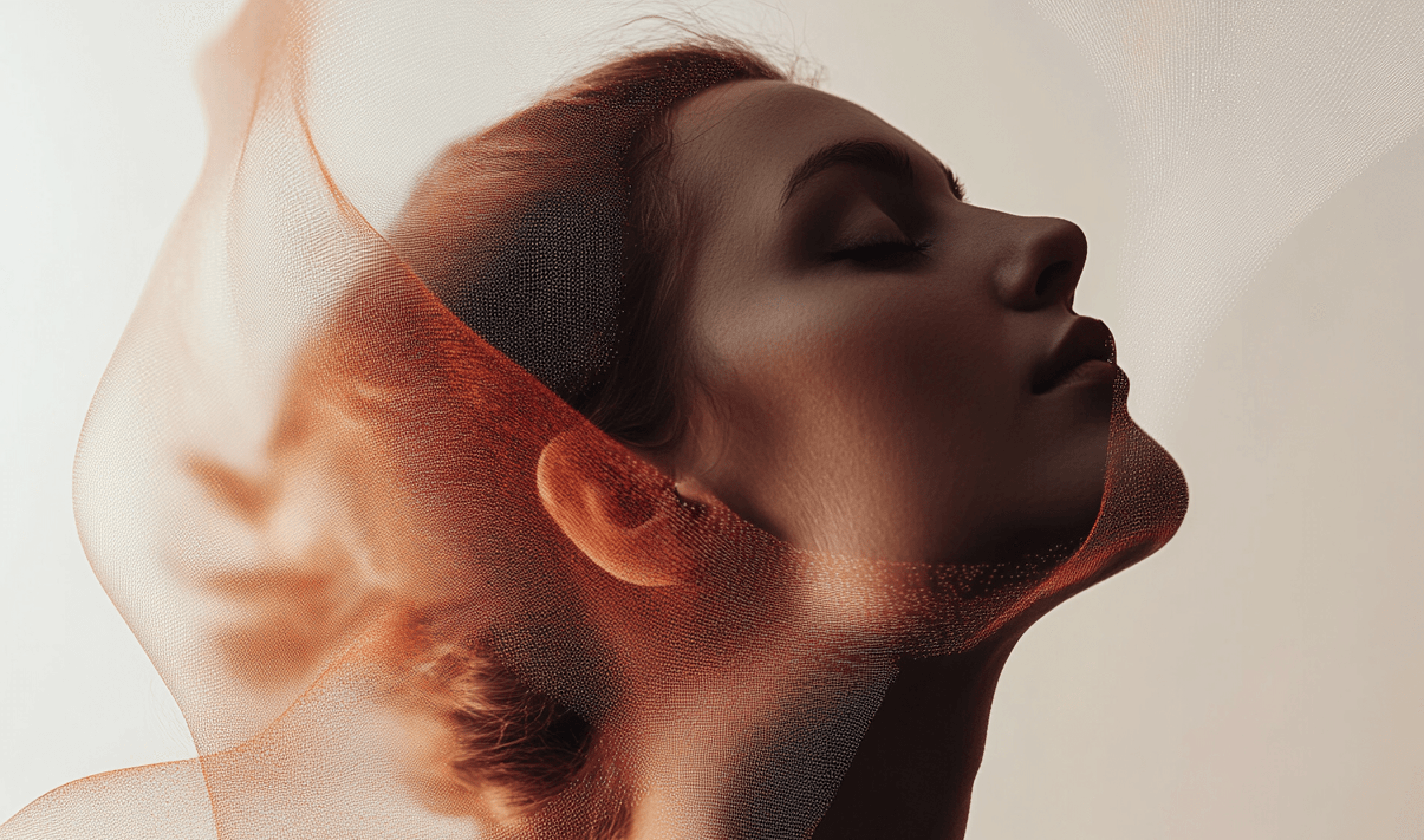 Profile of serene woman under transparent fabric.