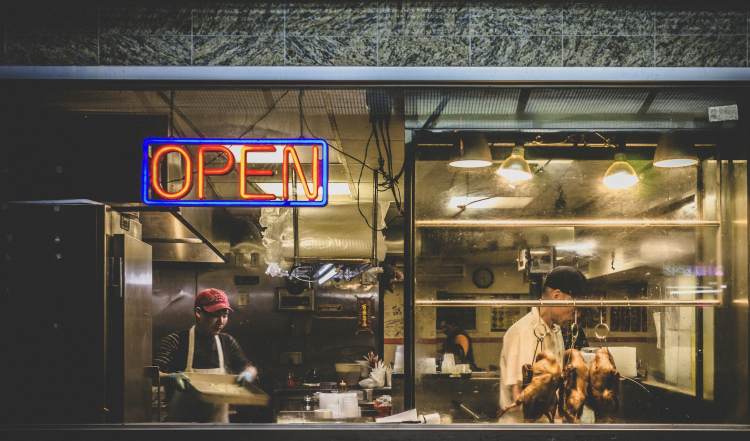 Restaurant kitchen with open sign and chefs inside.