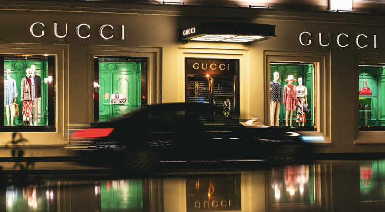 Luxury store display with mannequins and car reflection.