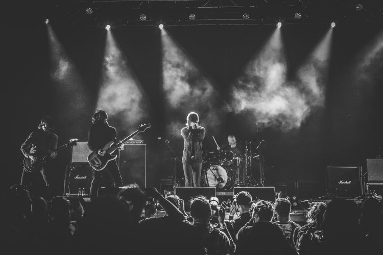 Rock band performing live on stage with audience.