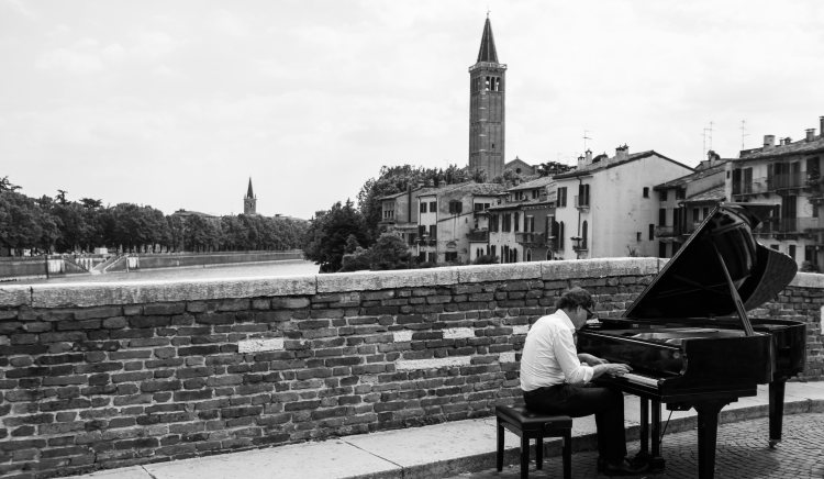 Man playing piano on a city bridge