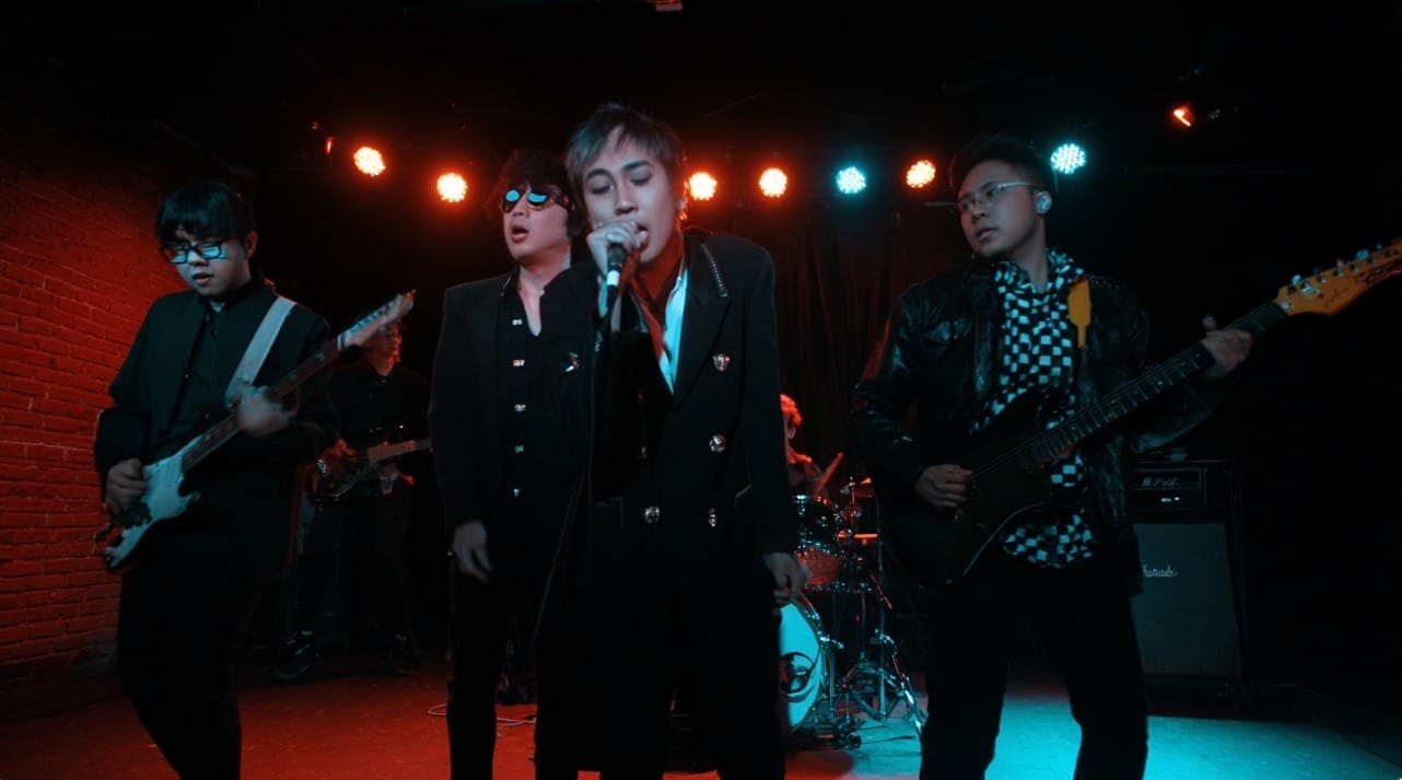 Band performing on stage with guitars and microphone.