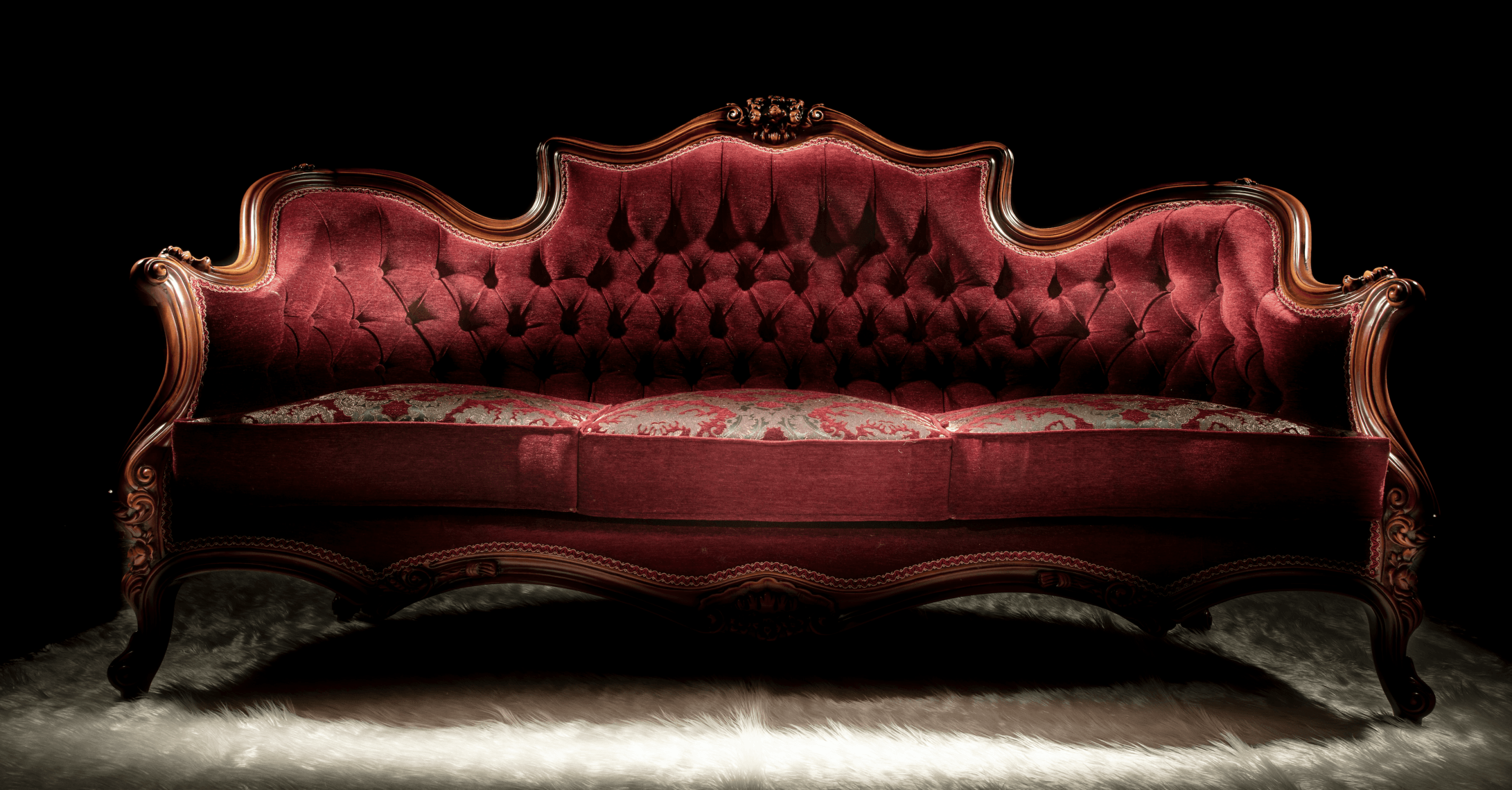 Vintage red velvet sofa with ornate wood frame.