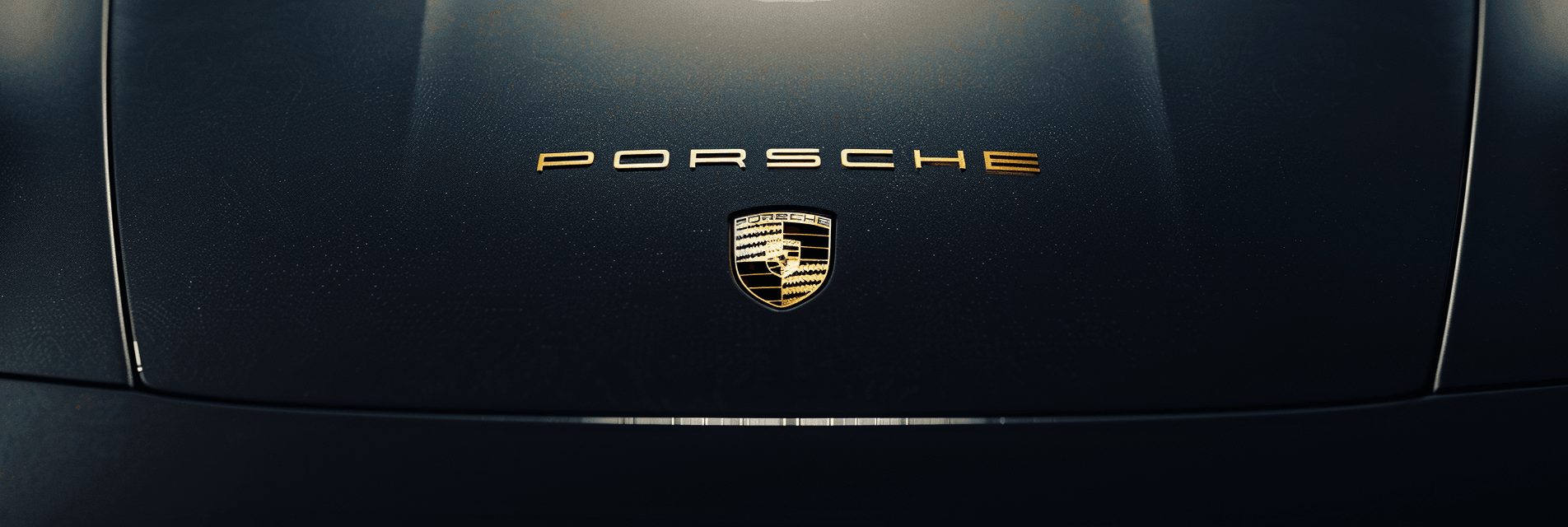 Close-up of Porsche logo on car hood.